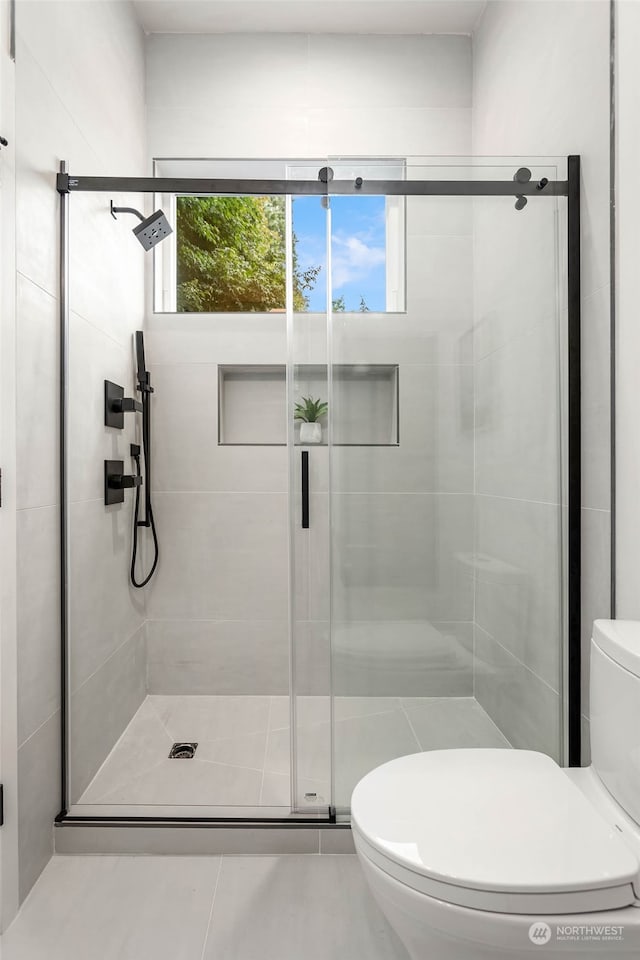 bathroom featuring tile patterned floors, toilet, and walk in shower