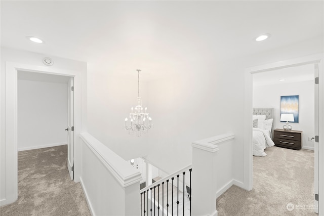 hallway with light carpet and a notable chandelier