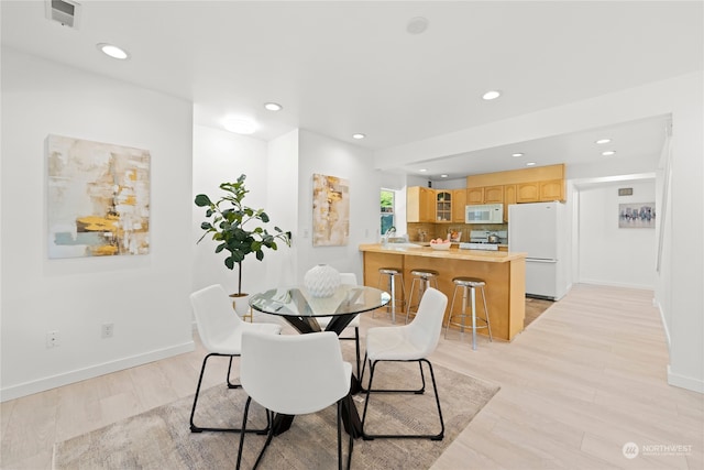 dining area with light wood-type flooring and sink