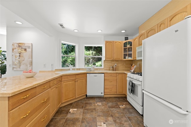 kitchen featuring decorative backsplash, white appliances, kitchen peninsula, light brown cabinets, and sink