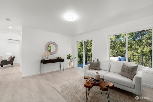 living room with light hardwood / wood-style flooring, a wall unit AC, and a healthy amount of sunlight