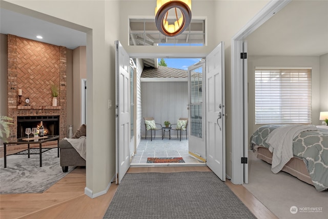 foyer entrance featuring light wood-type flooring, a fireplace, and a healthy amount of sunlight