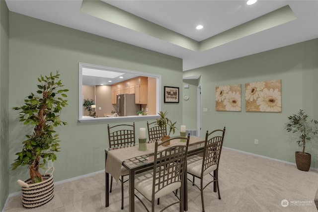 dining space with light carpet and a raised ceiling