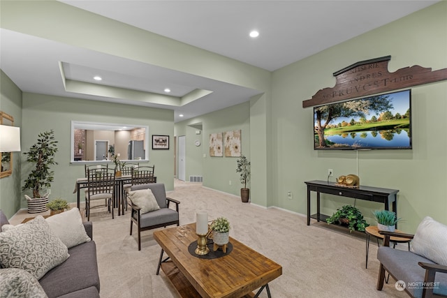 living room featuring light colored carpet and a raised ceiling