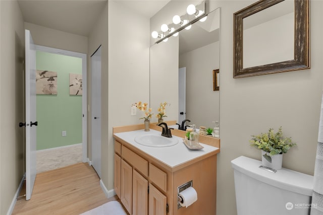 bathroom with vanity, toilet, and hardwood / wood-style flooring