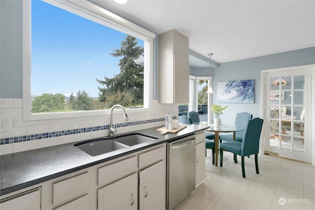 kitchen featuring white cabinetry, stainless steel dishwasher, a wealth of natural light, and decorative light fixtures