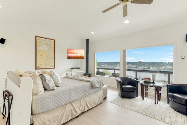 bedroom with ceiling fan, light wood-type flooring, a water view, and lofted ceiling