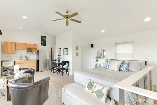 bedroom featuring ceiling fan, lofted ceiling, stainless steel fridge, sink, and light hardwood / wood-style flooring