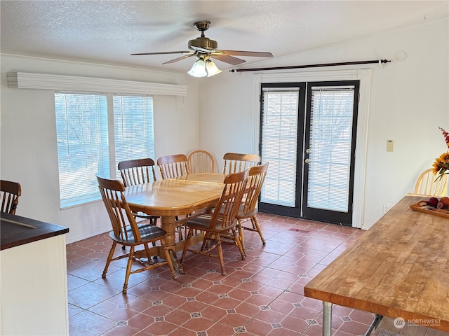 dining space with a textured ceiling, ceiling fan, dark tile patterned floors, and a wealth of natural light