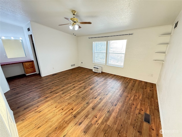 empty room with a textured ceiling, ceiling fan, dark wood-type flooring, and a wall mounted air conditioner