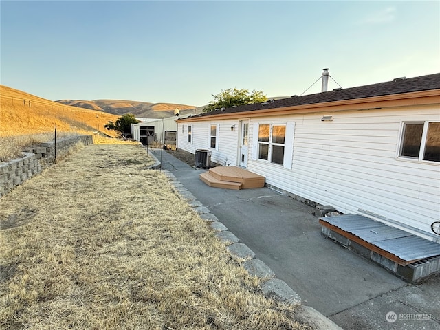 back of property with a mountain view, a patio area, and central AC