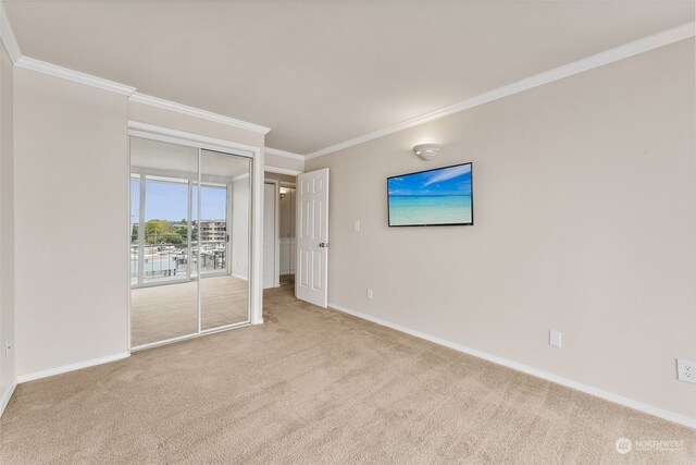 unfurnished bedroom with a closet, light colored carpet, and crown molding