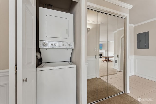 laundry area with light carpet, electric panel, ornamental molding, and stacked washer and clothes dryer