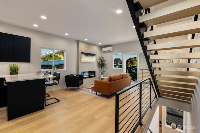 living room with light hardwood / wood-style floors and an AC wall unit