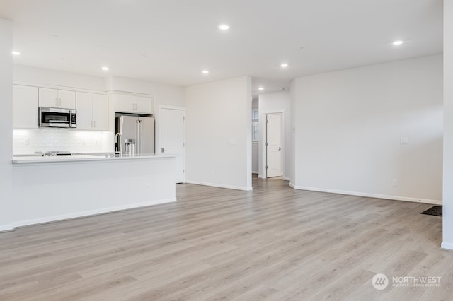 unfurnished living room with sink and light hardwood / wood-style floors