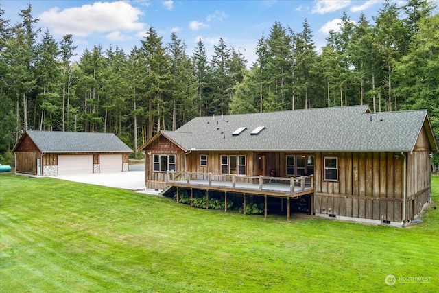 rear view of property featuring a yard, an outdoor structure, a garage, and a deck