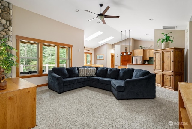 living room featuring vaulted ceiling with skylight, ceiling fan, and light colored carpet