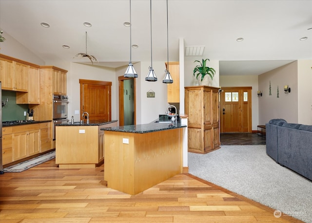 kitchen with light hardwood / wood-style flooring, kitchen peninsula, and decorative light fixtures