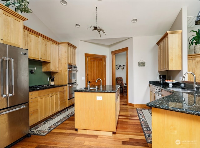 kitchen featuring a center island with sink, appliances with stainless steel finishes, sink, and dark stone counters