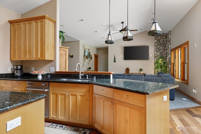 kitchen featuring lofted ceiling, light wood-type flooring, sink, and dark stone counters