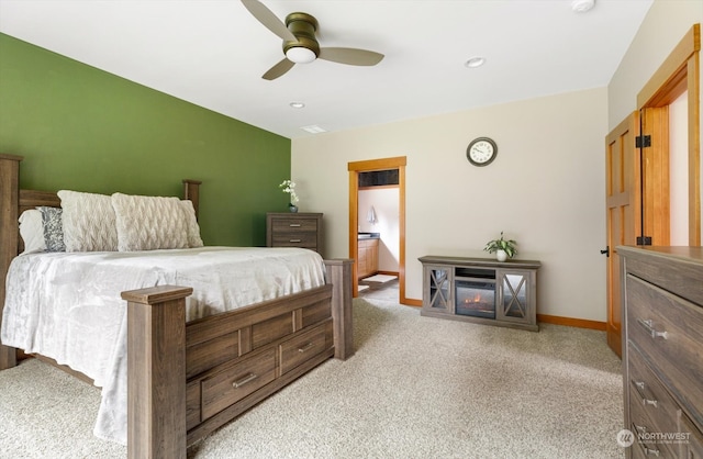 bedroom featuring light carpet, ceiling fan, and ensuite bath