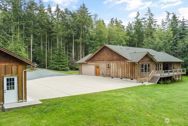 back of property with a garage, a deck, and a yard