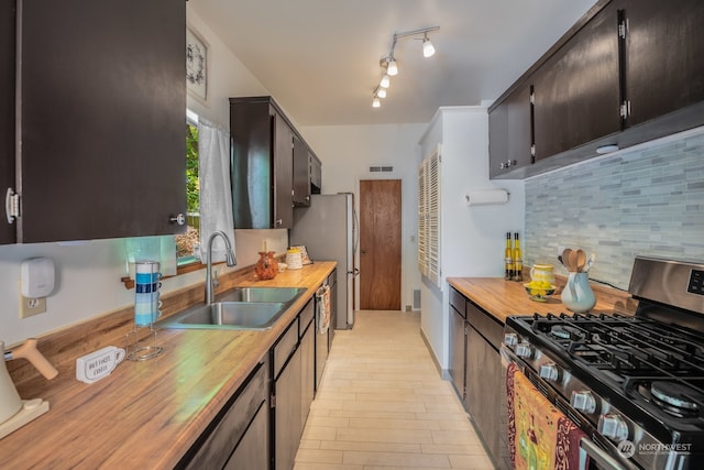 kitchen featuring tasteful backsplash, sink, butcher block countertops, and appliances with stainless steel finishes