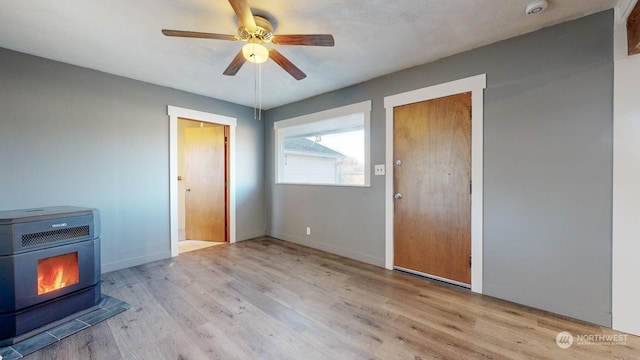 interior space featuring light wood-type flooring, heating unit, ceiling fan, and a wood stove