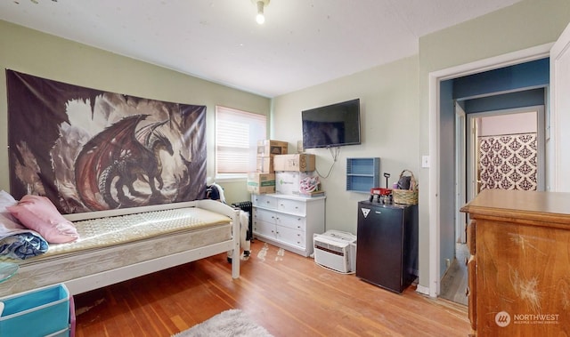 bedroom featuring light wood-type flooring and fridge