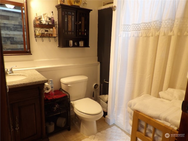 bathroom with toilet, vanity, and tile patterned floors