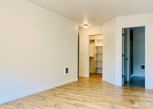 unfurnished bedroom featuring light wood finished floors, baseboards, visible vents, a spacious closet, and a closet