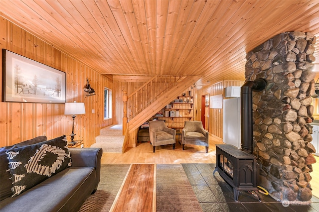 living room featuring wooden ceiling, wood walls, hardwood / wood-style floors, and a wood stove