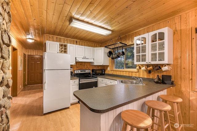 kitchen with stainless steel range with electric cooktop, white refrigerator, a kitchen breakfast bar, and kitchen peninsula