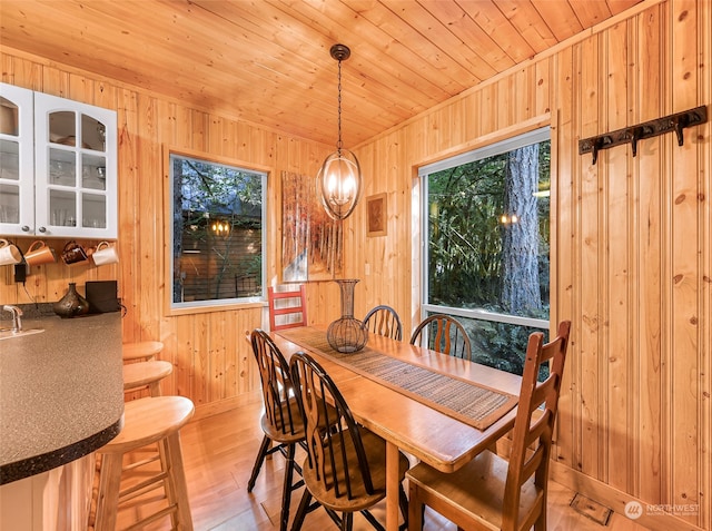 dining space featuring wooden walls, light hardwood / wood-style floors, and wooden ceiling