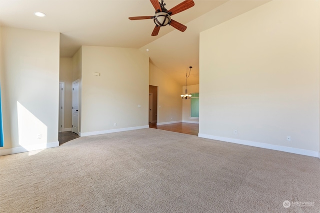 carpeted spare room featuring ceiling fan with notable chandelier and high vaulted ceiling