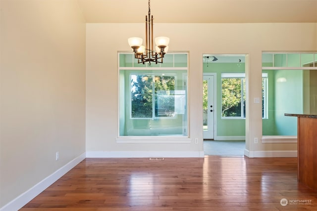 unfurnished dining area with hardwood / wood-style flooring and a chandelier