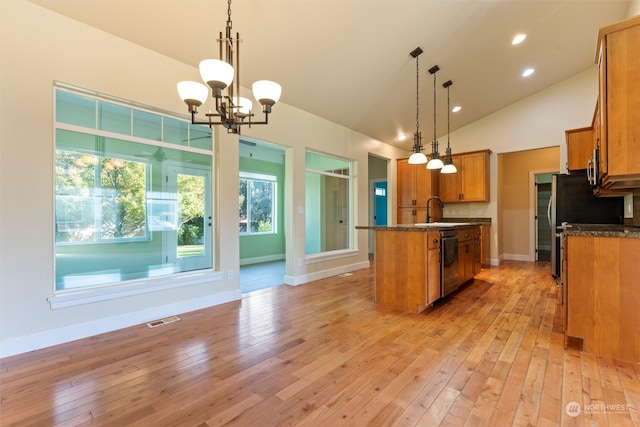 kitchen with light hardwood / wood-style floors, decorative light fixtures, a center island with sink, and stainless steel dishwasher