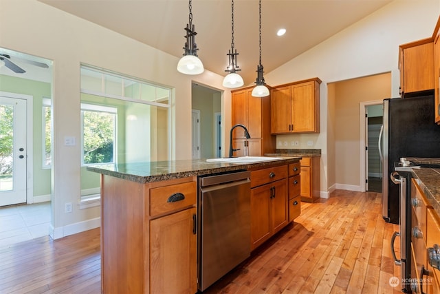 kitchen featuring an island with sink, sink, vaulted ceiling, stainless steel appliances, and light hardwood / wood-style floors