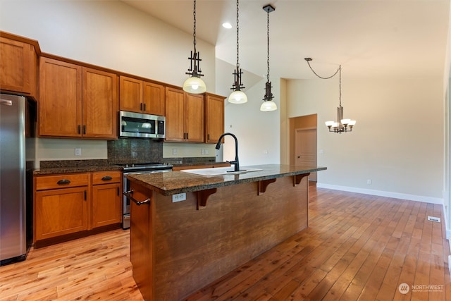 kitchen featuring sink, a kitchen island with sink, high vaulted ceiling, stainless steel appliances, and a breakfast bar area