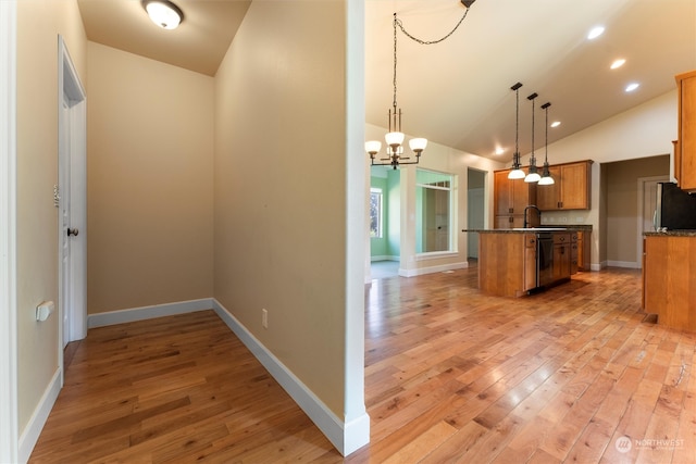 kitchen featuring lofted ceiling, pendant lighting, black dishwasher, and light wood-type flooring