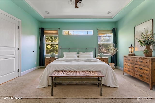 bedroom featuring a raised ceiling, ornamental molding, multiple windows, and light carpet