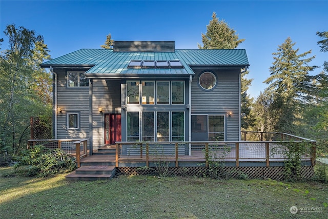 rear view of house with a deck and a lawn