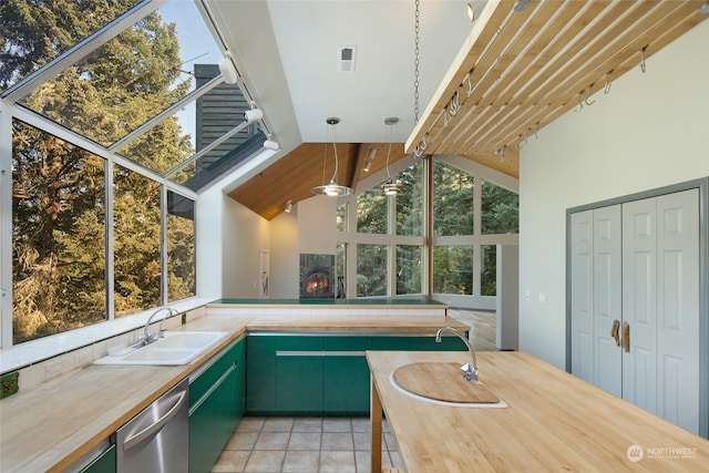 kitchen featuring lofted ceiling, green cabinets, sink, decorative light fixtures, and stainless steel dishwasher