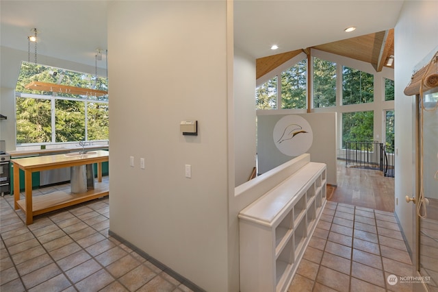 hallway featuring beam ceiling, a healthy amount of sunlight, high vaulted ceiling, and light hardwood / wood-style flooring