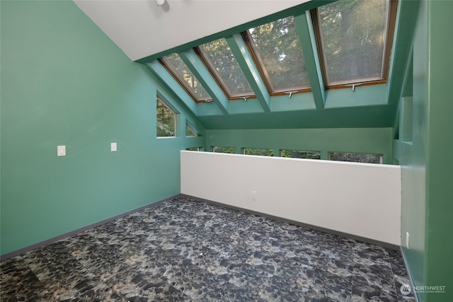 spare room featuring lofted ceiling with skylight and a healthy amount of sunlight