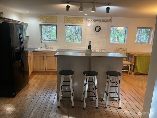 kitchen featuring a wealth of natural light, sink, light hardwood / wood-style floors, and black fridge