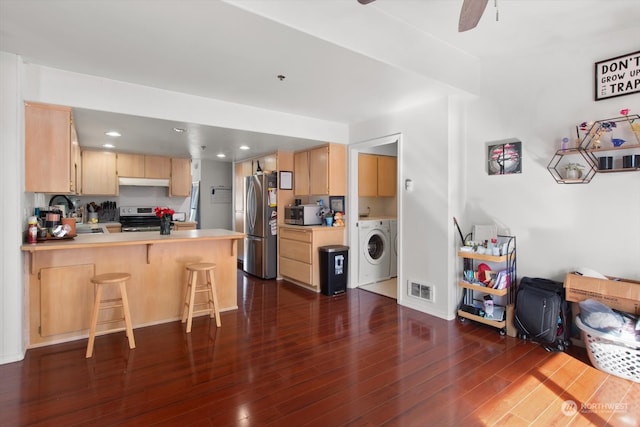 kitchen with washer / clothes dryer, kitchen peninsula, light brown cabinets, stainless steel appliances, and dark hardwood / wood-style floors