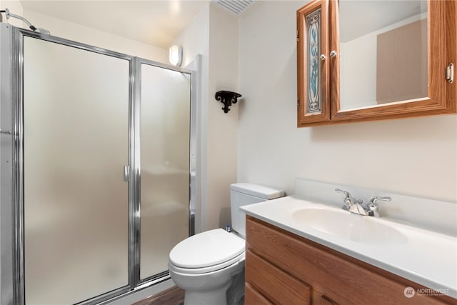 bathroom with a shower with shower door, hardwood / wood-style flooring, vanity, and toilet