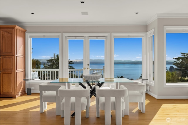 dining space featuring light hardwood / wood-style flooring, ornamental molding, and a water view