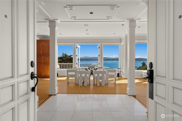 interior space featuring ornamental molding, a water view, light hardwood / wood-style floors, and ornate columns